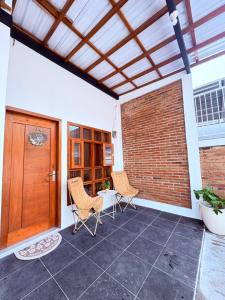 a patio with two chairs and a brick wall at Fortune Homestay Banyuwangi in Banyuwangi