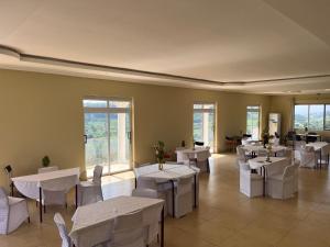 a restaurant with white tables and white chairs and windows at Mar Luther Inn in Aburi