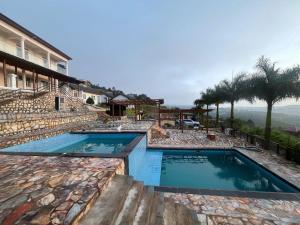 a couple of swimming pools sitting next to a house at Mar Luther Inn in Aburi