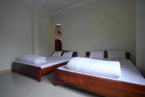 two beds in a room with white sheets at Nhà nghỉ Ngọc Ánh in Dồng Văn