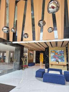 a lobby with blue chairs and a painting on the wall at Azana Style Hotel Tulungagung in Tulungagung