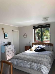 een slaapkamer met een bed, een dressoir en een raam bij First Light in Mangawhai