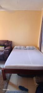 a bed sitting in a room with a couch at Smooth Landing in Ukunda
