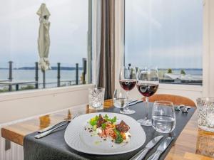 a table with a plate of food and glasses of wine at 4 person holiday home on a holiday park in Faaborg in Fåborg