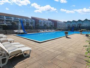 a pool with chairs and a slide in front of a building at 6 person holiday home on a holiday park in Faaborg in Fåborg