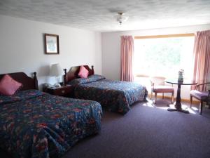 a hotel room with two beds and a table and a window at Redclyffe Shore Motor Inn in Robbinston