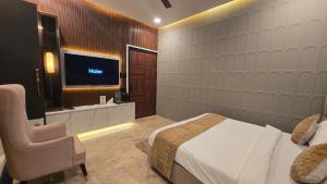 a bedroom with a bed and a chair and a television at Vraj in Vrindāvan