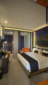 a bedroom with a large bed and a desk at Azana Style Hotel Tulungagung in Tulungagung