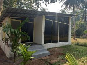 ein kleines Haus mit Glastüren und einer Veranda in der Unterkunft New Wind Stay in Dandeli