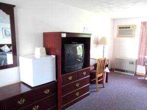 a hotel room with a tv and a bedroom at Redclyffe Shore Motor Inn in Robbinston