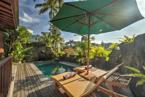 a table with an umbrella next to a swimming pool at Gedong Batu Villas in Ubud
