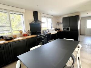 a kitchen with black cabinets and a table with chairs at Charmante maison à Groix proche du port - FR-1-813-35 in Kerlo