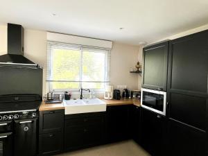a kitchen with black cabinets and a sink and a window at Charmante maison à Groix proche du port - FR-1-813-35 in Kerlo