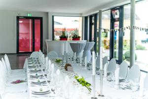 een lange witte tafel met witte stoelen en tafels met borden bij Hotel Mecklenburger Hof Gnoien in Gnoien