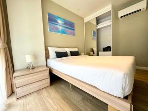 a bedroom with a large white bed and a night stand at Diamond Condo apart near Bangtao beach in Bang Tao Beach
