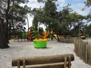 un parc avec une aire de jeux et un seau vert dans l'établissement Chalet neuf avec piscine couverte, proche mer, calme et sécurisé - 6 personnes - FR-1-777-8, à La Parée Preneau