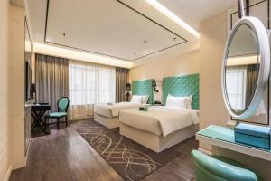 ein Hotelzimmer mit zwei Betten und einem Spiegel in der Unterkunft Xana Lite Korla Shihua Avenue Longquehe in Korla