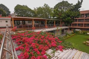 een uitzicht op een gebouw met roze bloemen in een tuin bij Hotel Vivek in Coonoor