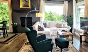 een woonkamer met een witte bank en groene stoelen bij Panoramic River Views - Nature Framed in Every Window in Kalama