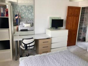 Un dormitorio con una cama y un escritorio con televisión. en Quaint and Peaceful - Calne, en Calne