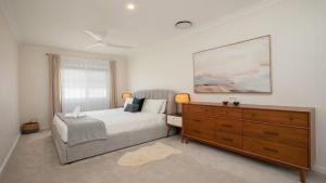 a bedroom with a large bed and a dresser at Waterfront, Renovated, Walk To Ettalong in Pretty Beach