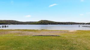 a body of water with a log in the grass at Waterfront, Renovated, Walk To Ettalong in Pretty Beach