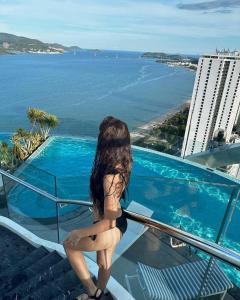 a woman standing on a balcony looking at the ocean at Panorama Sky Beach Recidences in Nha Trang