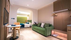 a living room with a green couch and a bed at Sun Island Resorts, Shanghai in Qingpu