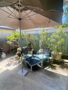 un patio con dos sillas y una sombrilla en Allawah at Wamberal, en Wamberal