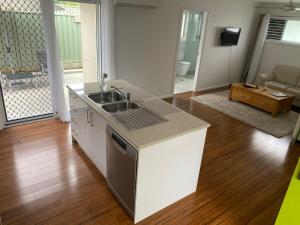 Una cocina con fregadero y una sala de estar. en Allawah at Wamberal, en Wamberal 21 fotos más