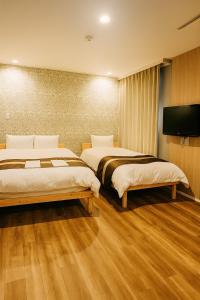 别府Beppu onsen Resort Stay Spa Tsurumi的一间配有两张床和一台平板电视的酒店房间