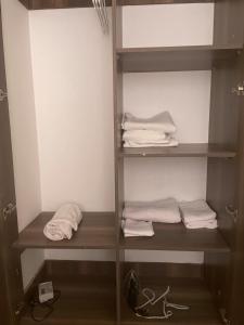 a closet with wooden shelves and white towels at Modern Smart Apartment with Easy Access in Mtwapa