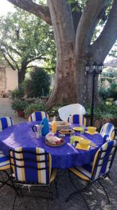 蒙法維的住宿－伯爾尼與米歇爾住宿加早餐旅館，桌子,桌子上布满了蓝色的桌布,椅子在树下