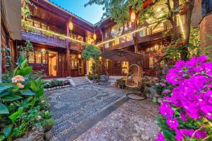 a house with a courtyard with flowers and an umbrella at Mengtianhu Inn in Lijiang +15 photos