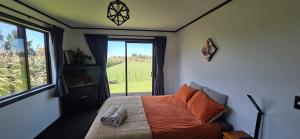 a bedroom with a bed and a large window at Pakawau Inlet House in Pakawau