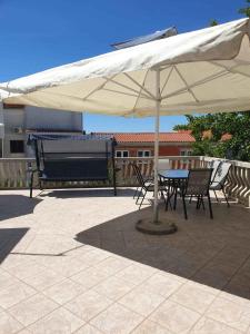 a table and chairs under an umbrella on a patio at Apartments in Pirovac 34905 in Pirovac
