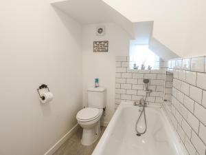 a white bathroom with a toilet and a bath tub at Deskford Cottage in Balblair +21 photos