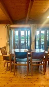 a dining room with a table and chairs and windows at オシドリ in Shirahama
