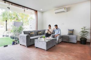 two people sitting on a couch in a living room at FabHotel Sky - Nr Sapphire 83 Mall, Manesar in Gurgaon