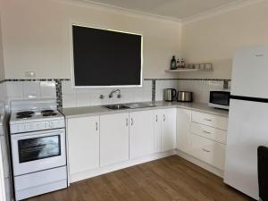 a white kitchen with a sink and a stove at Walcha Villas in Walcha