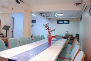 杭州市にある杭州西湖月上兰湾民宿の花瓶に花が飾られた長いテーブルのある会議室