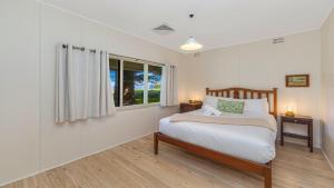 ein Schlafzimmer mit einem Bett und einem Fenster in der Unterkunft Brisk Bay Cottage By Holidayco in Patonga