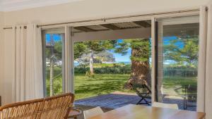 ein Esszimmer mit einem Tisch und einer Glasschiebetür in der Unterkunft Brisk Bay Cottage By Holidayco in Patonga