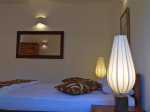 1 dormitorio con 1 cama con lámpara y espejo en The Clouds Ahangama, en Ahangama