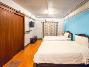 two beds in a room with blue walls and wooden floors at Thepmongkol House in Bangkok