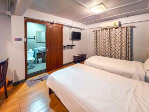 a hotel room with two beds and a bathroom at Thepmongkol House in Bangkok