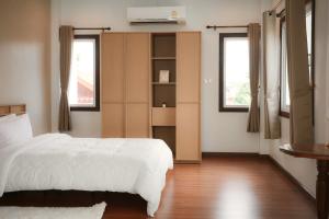 a bedroom with a white bed and two windows at Browny house - Doi Suthep View in Chiang Mai