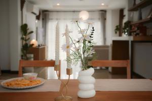 a table with a vase with flowers and a plate of food at Browny house - Doi Suthep View in Chiang Mai
