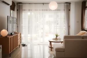 a living room with a couch and a tv and a window at Browny house - Doi Suthep View in Chiang Mai