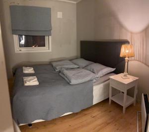 a bedroom with a bed with a lamp and a window at Lillian's gjestehus, Skibotn in Skibotn